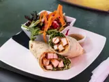A chicken wrap and salad on a table 