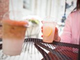 Person sitting at a table holding a lemonade 
