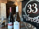 Two wine bottles in front of a 33 vines sign
